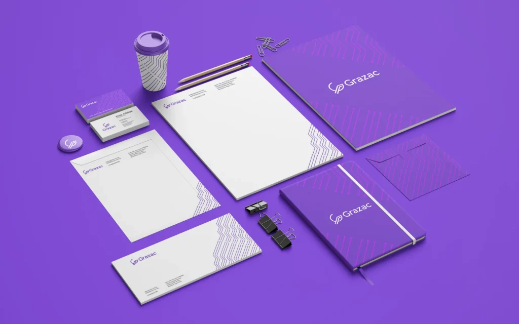 Grazac stationery identity across notebooks, letterhead, cards, a cup and desk accessories on a purple background